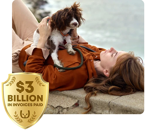 Woman laying on a seawall with her pet dog sitting on her. Trupanion $3 billion logo in the corner.