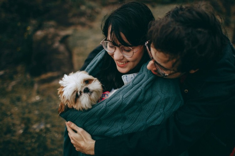 Couple cuddling a small dog outdoors