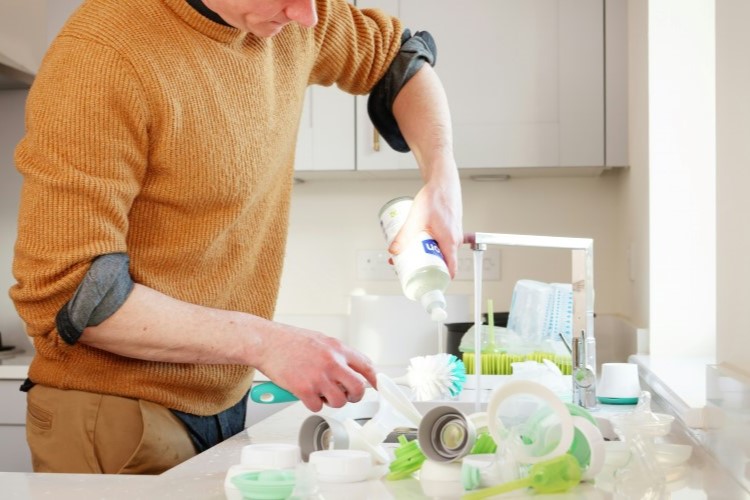 man washing dishes with cleaning products