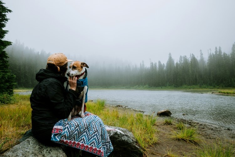 owner resting with her dog near the river