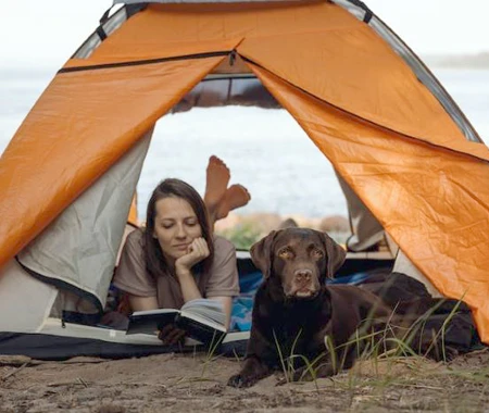 Woman in a tent outdoors with her dog